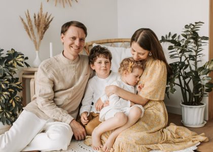 Happy family of four enjoying quality time together in a cozy, plant-filled room.