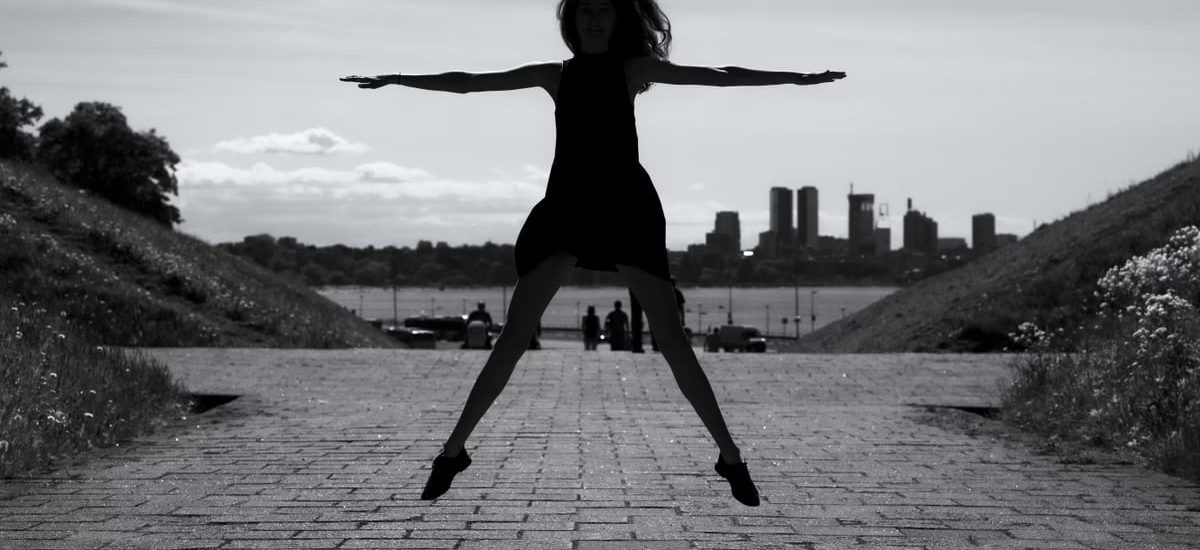 A dynamic black and white silhouette of a woman jumping with arms outstretched in Tallinn, Estonia.