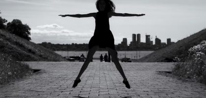 A dynamic black and white silhouette of a woman jumping with arms outstretched in Tallinn, Estonia.