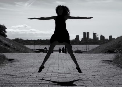 A dynamic black and white silhouette of a woman jumping with arms outstretched in Tallinn, Estonia.